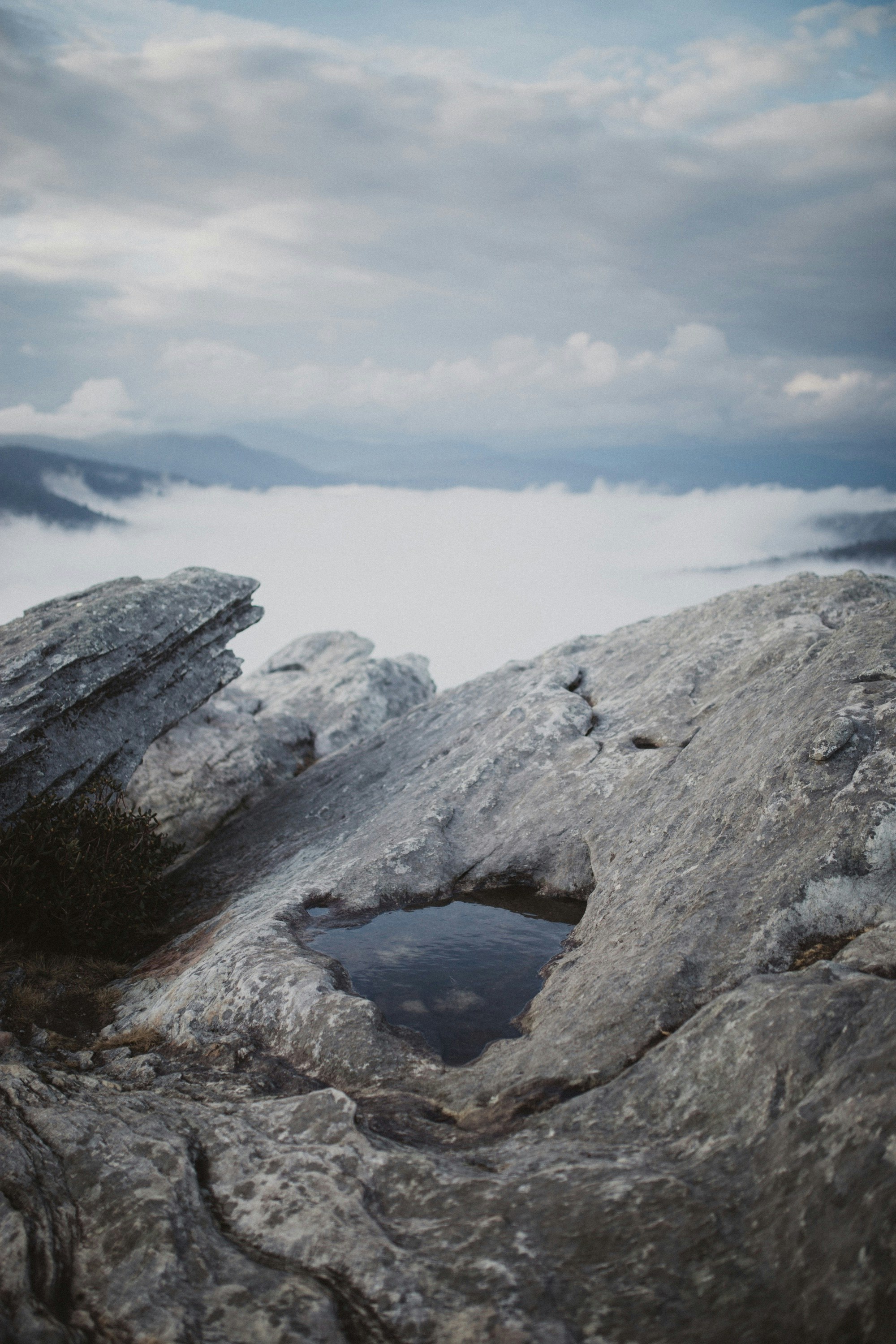 gray rock formation near body of water under white clouds during daytime